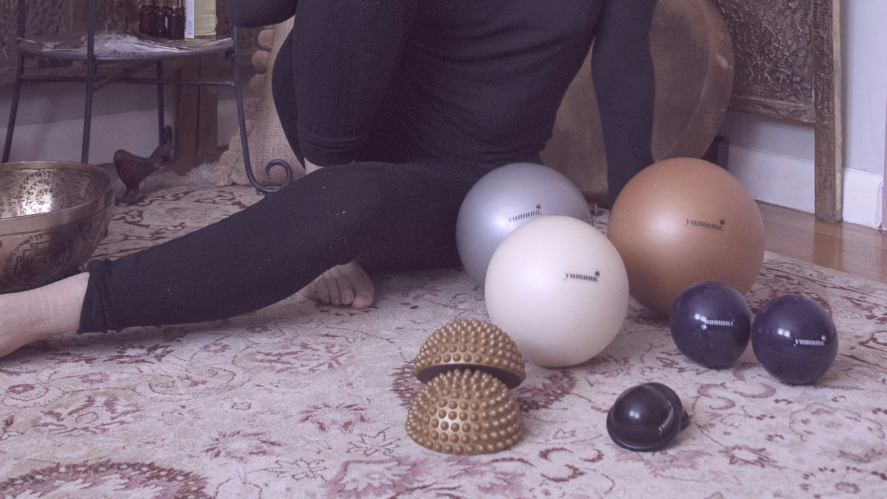 Yamuna balls and foot savers laid out on a rug at GLOW Body Pilates